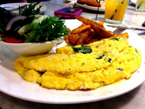 Fluffy cheese omelette with wedges and greens on the side.
