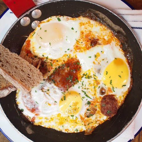 Free-range eggs in a pan with fried iberico chorizo ontoast 
